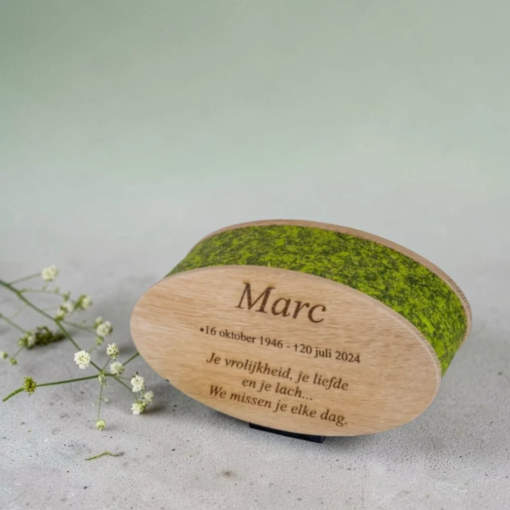 houten ovale urn bekleed met mos en voorzien van een gravering