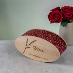 Ovale houten urn met rozenblaadjes en gravering